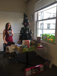 WHRI staff member stands holding present in front of christmas tree