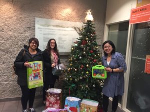 women stand holding presents in front of christmas tree at crabtree corner