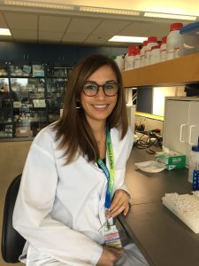 Dr. Cindy Barha sitting at desk wearing lab coat.
