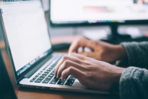 A close-up photo of hands typing on a laptop